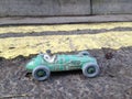 Vintage toy racing car & driver close up with worn green patina, in front of double yellow line no parking restriction. Royalty Free Stock Photo