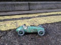 Vintage toy racing car & driver with worn green patina, in front of double yellow line no parking restriction. Royalty Free Stock Photo