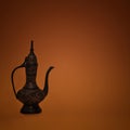 Vintage traditional islamic oriental engraved pitcher handmade on dark orange background. Elegant arabian antique tall metal jug