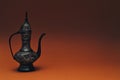Vintage traditional islamic oriental engraved pitcher handmade on dark orange background. Elegant arabian tall metal jug