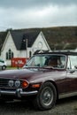 Vintage Triumph car parked with old church in the background on a cloudy day