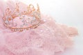 Vintage tulle pink chiffon dress and diamond tiara on wooden white table. Wedding and girl& x27;s party concept