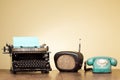 Vintage typewriter, old radio, retro telephone on wooden table front blue background. Vintage style photo Royalty Free Stock Photo