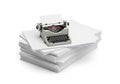 A vintage typewriter rests atop a large stack of blank white paper. The typewriter is gray Royalty Free Stock Photo