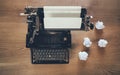 Vintage typewriter on rustic wooden background with crumpled papers around