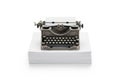 Vintage typewriter sits atop a large stack of white paper, isolated on a white Royalty Free Stock Photo