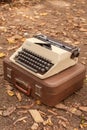 A vintage typewriter stands on a suitcase