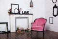 Vintage velor armchair, in a bright room and an artificial fireplace. Interior attic with wooden white walls. Picture frames on th Royalty Free Stock Photo