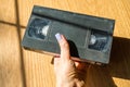 Vintage videotape in a woman& x27;s hand on a wooden table., on beige background.