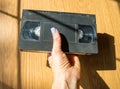 Vintage videotape in a woman& x27;s hand on a wooden table., on beige background.