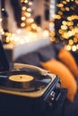 vintage vinyl record player in a cozy home livingroom with lots of warm fairy lights and orange pillows couch