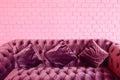 Vintage violet sofa with pink brick wall