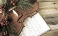 Vintage violin adorned with christmas fern lying on sheet music.