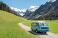 Vintage VW Bully camping car driving on mountain valley road Royalty Free Stock Photo