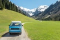 Vintage VW Bully camping car driving on mountain valley road