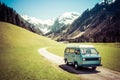 Vintage VW Bully camping car driving on mountain valley road Royalty Free Stock Photo