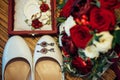 Vintage wedding jewelry and accessories, close-up. Gold wedding rings, ruby earrings, classic bride`s shoes, bouquet of fresh red Royalty Free Stock Photo