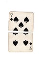A vintage seven of spades playing card torn in half.