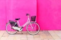 Vintage white bicycle against a vibrant pink wall