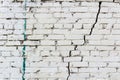 Vintage white brick wall with a deep crack and spots of paint. Abstract background