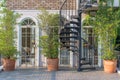 Vintage white frame door and modern black metal spiral staircase with natural green tree gardening exterior for home and living ac Royalty Free Stock Photo