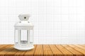 Vintage white lantern on wooden table, white ceramic tile background Royalty Free Stock Photo