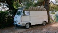 Vintage white van minibus on a gravel road under a tree