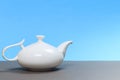 Vintage white porcelain teapot on gray board and blue background Royalty Free Stock Photo