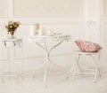 Vintage white room with chair and table with flowers pillow, coffee cups and candles Royalty Free Stock Photo