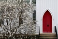 White wood church red arch doors budding dogwood Royalty Free Stock Photo