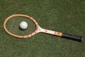 Vintage Wilson Jack Kramer tennis racket and antique white tennis ball on the grass tennis court.