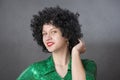 Vintage woman in afro wig and red disco costume on a gray background