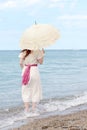 Vintage woman with parasol standing in the water on beach Royalty Free Stock Photo