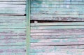 Vintage wood background with peeling turquoise old flaky paint. Slanting slit in the wall of a large barn due to skewed boards.