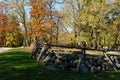 A vintage wood and stone fence weaves through autumn colors