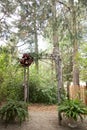 Vintage wooden arch wtih red and pink roses - outdoor wedding ceremony location in coniferous forest wtih classic bentwood chairs