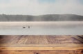 vintage wooden board table in front of abstract photo of misty and foggy lake at morning/evening. Royalty Free Stock Photo