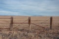 Vintage wooden cattle fencing in front of large pasture with cloudy sky