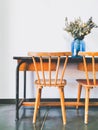 Vintage wooden elementary school desk and two wooden chairs with a dried flower arrangement in a blue vase against a white wall Royalty Free Stock Photo