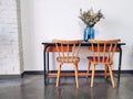 Vintage wooden elementary school desk and two wooden chairs with a dried flower arrangement in a blue vase against a white wall Royalty Free Stock Photo