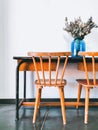 Vintage wooden elementary school desk and two wooden chairs with a dried flower arrangement in a blue vase against a white wall Royalty Free Stock Photo