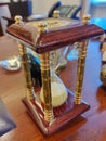 A vintage wooden hourglass stands on an office desk