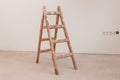 Vintage wooden ladder against a smooth white wall in an unoccupied room