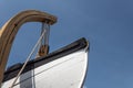 Vintage wooden lifeboat attached to a hoist, against a brilliant blue sky