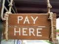 Vintage wooden sign to indicate cashier location. Pay Here written on planks. Royalty Free Stock Photo