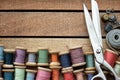 Wooden spools of multicolored threads, tailoring scissors, thimbles, measuring tape. Sewing items, view from above Royalty Free Stock Photo