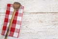 Vintage wooden spoon on the white and red checkered napkin on the rustic white paint wooden background Royalty Free Stock Photo