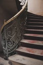 Vintage wooden staircase with iron rail. Old circular stairway in abandoned historical building. Spiral stairway. Royalty Free Stock Photo