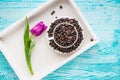 Vintage wooden tray with porcelain cup full of coffee beans and pink flowers on shabby chic mint background, top view Royalty Free Stock Photo