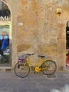 Vintage yellow bicycle in front stone wall on the street in the medieval village of San Sepolcro near city of Arezzo i